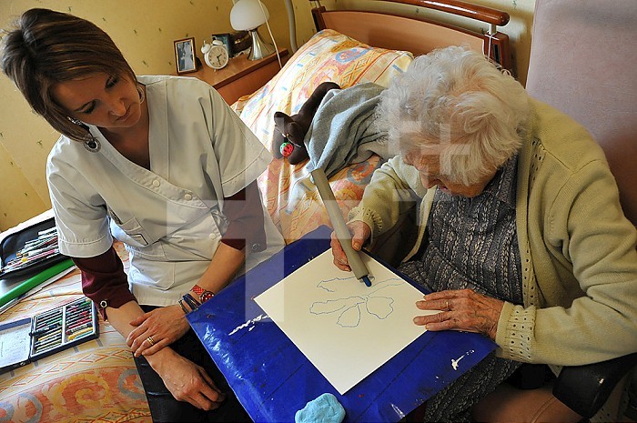 Reportage on art therapy in Ham hospital’s retirement home, France. Art therapy sessions are offered to residents in order to maintain or rehabilitate their motor, cognitive and sensory functions as well as social ties. The art therapist attaches great importance to self-esteem. She considers that touch, contact and considerate gestures are vital for the success of the workshops.