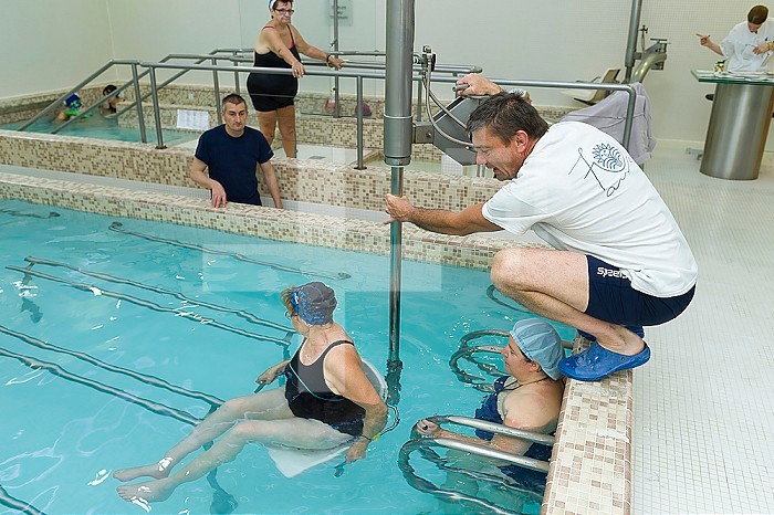 Reportage at the thermal baths in Lamalou-les-Bains, France. Reception area in the Leroy Pavilion, care service devoted to neurological disorders. The hydrotherapist uses the hydraulic seat.